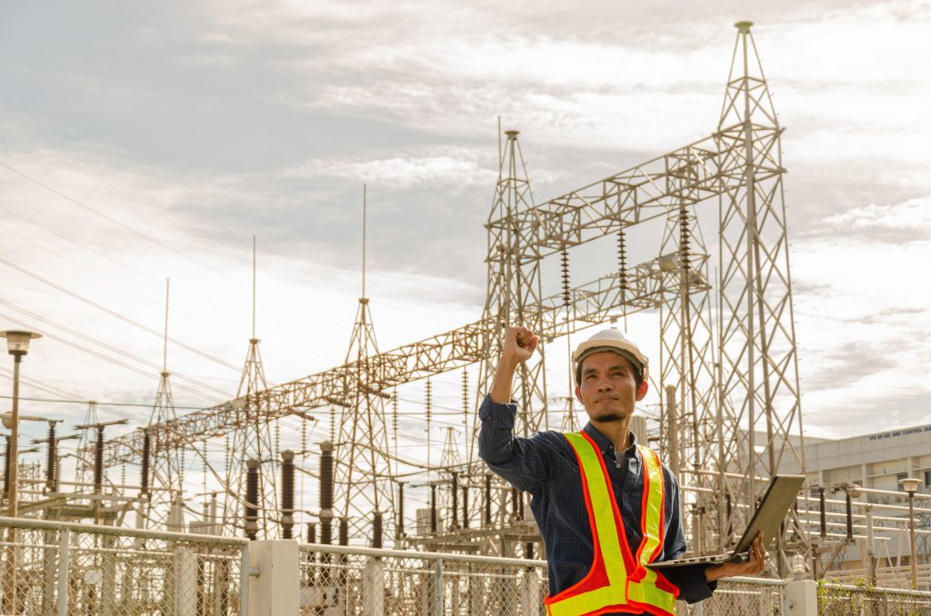 Network engineer in hi-vis using a laptop at a remote electricity substation, connected on site with Rapid Wi-Fi